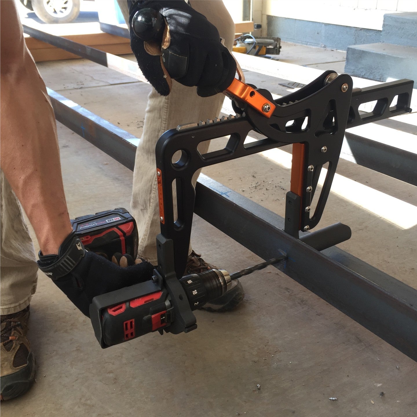 Milwaukee drill attached to a rapidrill with a compatible clamp being used to drill through right angle iron in a shop